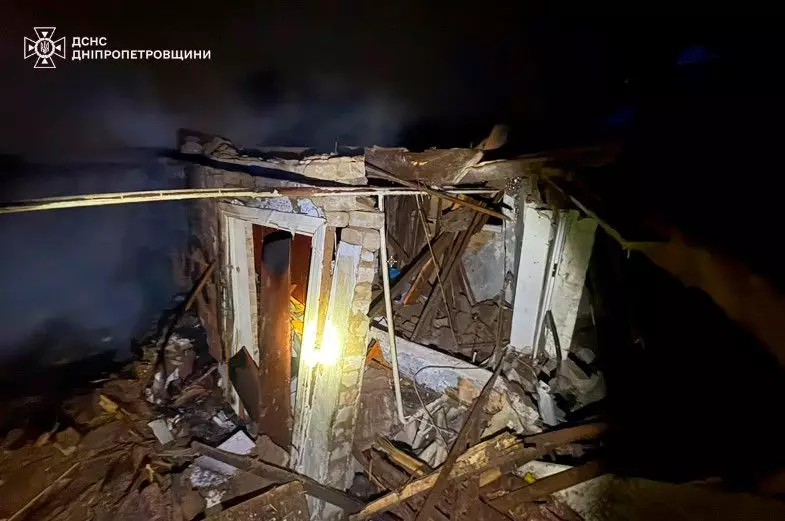 Руїни зруйнованої будівлі внаслідок обстрілів, нічне освітлення, робота рятувальників