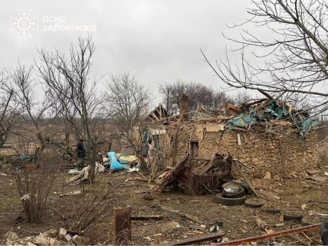 Зруйнований будинок після обстрілу, навколо уламки та пошкоджені дерева, тривають ремонтні роботи