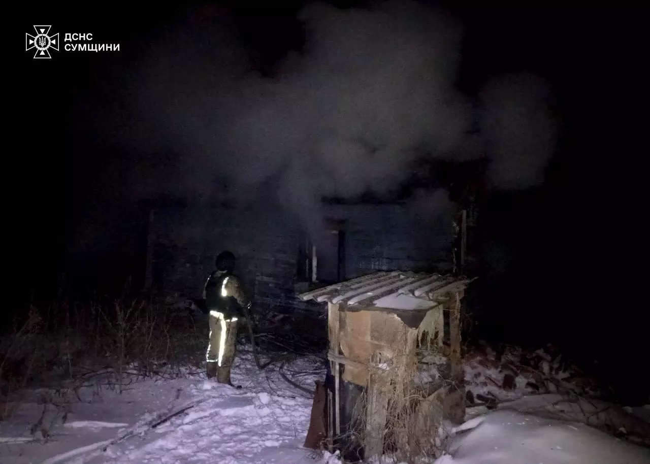 Рятувальник оглядає зруйновану будівлю вночі після обстрілу, навколо лежить сніг