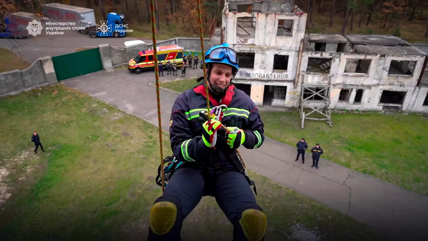 Рятувальник-верхолаз у спорядженні спускається з висоти біля зруйнованої будівлі, на задньому плані пожежна машина